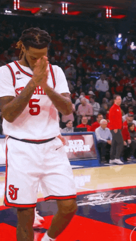 a basketball player with the number 5 on his jersey stands on the court