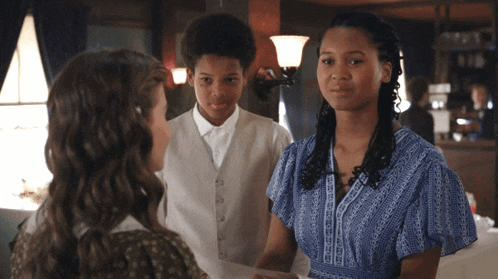 a woman in a blue dress talks to a boy and a girl