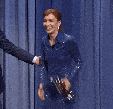 a woman in a blue dress is laughing while holding an award