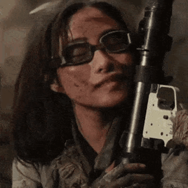 a woman wearing glasses is holding a gun in her hands .
