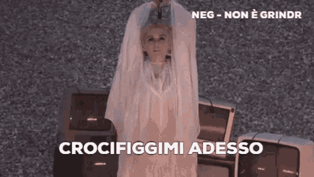 a woman in a white dress is standing in front of a pile of televisions and says crocifiggimi adesso .