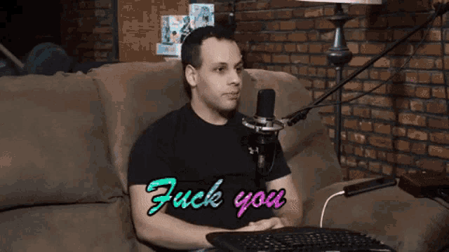 a man sitting on a couch with his hands on his ears and the words " fuck you " written on his shirt