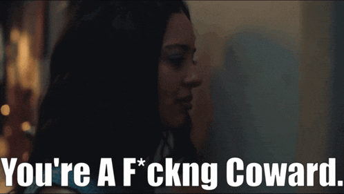 a woman in a dark room with the words you 're a f * cking coward