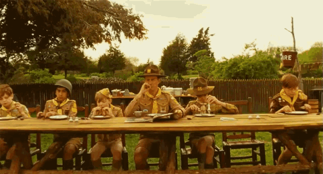 a group of boy scouts sit at a table eating food