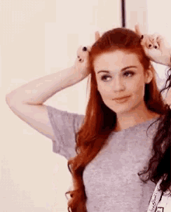 a woman with red hair is holding her hair in a bun .