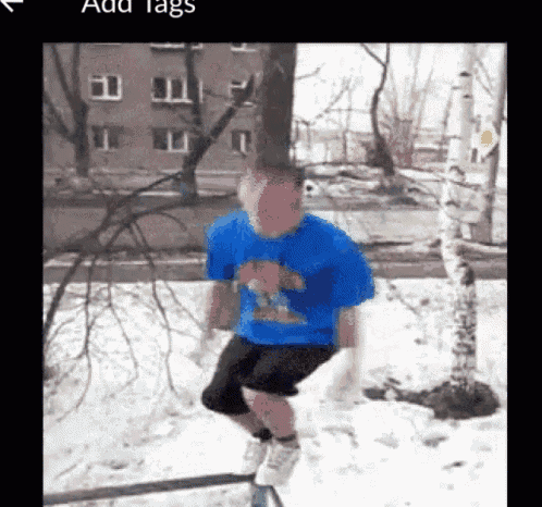 a man in a blue shirt is jumping over a railing in the snow