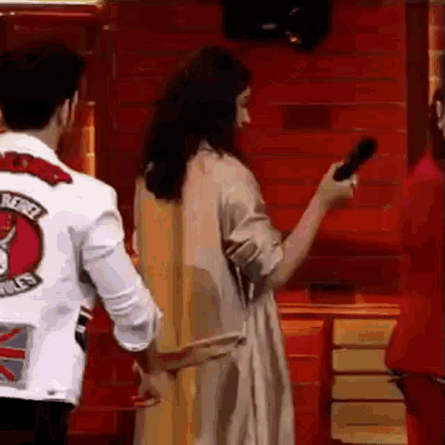a man and a woman are standing next to each other in front of a red wall .