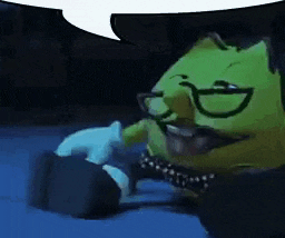 a green cartoon character with glasses and a mustache is sitting on a table .