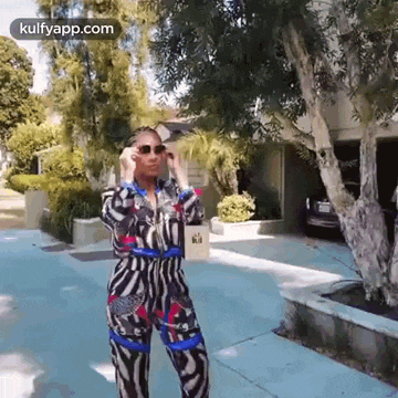 a woman wearing a zebra print jumpsuit is standing on a sidewalk .