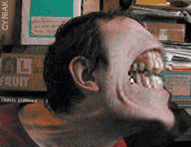 a close up of a man 's face in front of a stack of fruit boxes