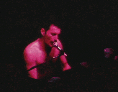 a shirtless man singing into a microphone while sitting at a keyboard