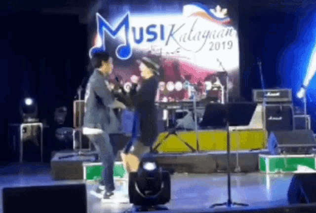 a man and a woman are dancing on a stage in front of a sign that says ' musik ' on it .