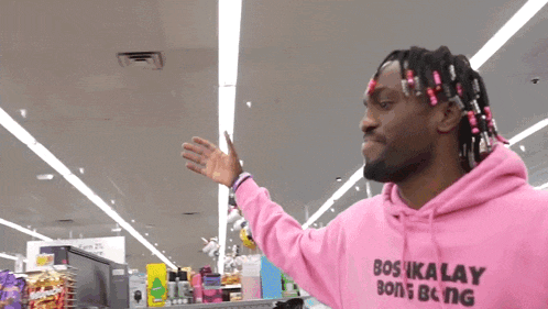 a man wearing a pink hoodie that says bos ika lay on it
