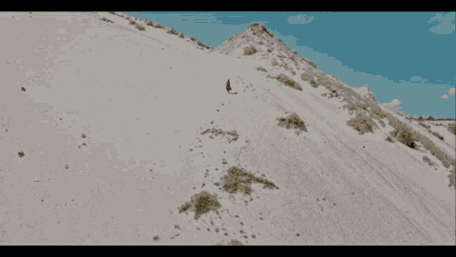 a man is walking up a sandy hill