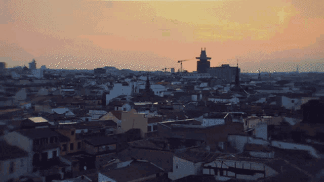 an aerial view of a city at sunset with a tower in the background