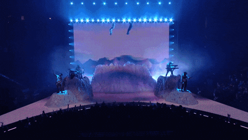 a group of people standing on a stage with a large screen in the background