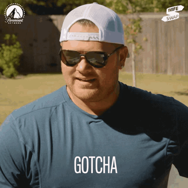 a man wearing sunglasses and a blue shirt that says gotcha on it