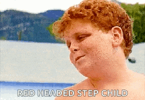 a shirtless redheaded step child is standing in front of a lake