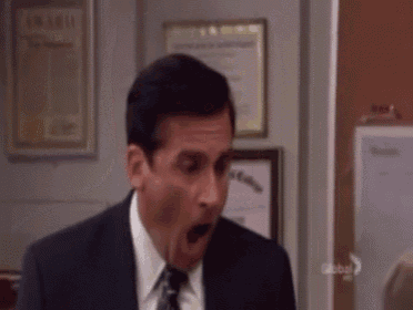 a man in a suit and tie is making a surprised face in a room .