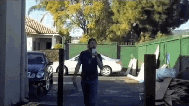 a man walking in a parking lot holding a cup of coffee