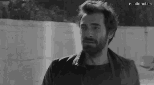 a man with a beard is standing in front of a wall .