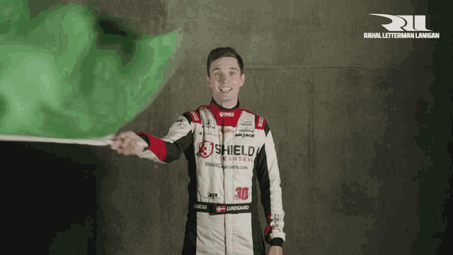 a man holding a green flag with shield written on his jacket