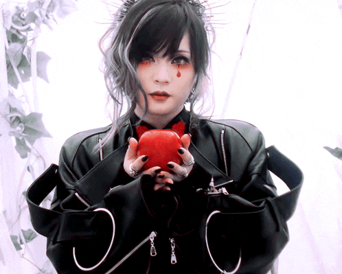 a woman in a black jacket is holding a red apple in her hands