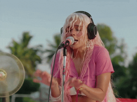 a woman singing into a microphone wearing headphones
