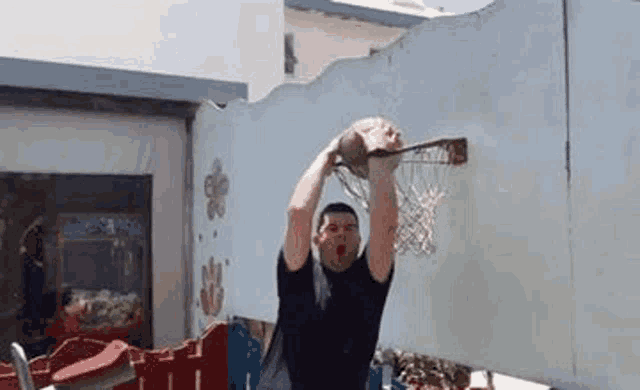 a man is dunking a basketball into a hoop .
