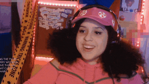 a woman wearing headphones and a pink hat is smiling