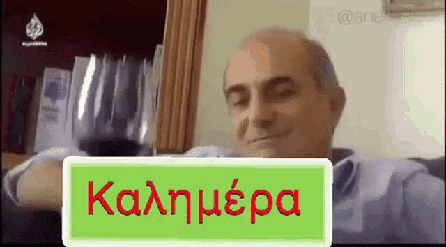a man with a glass of wine and a sign that says " καλημερα "