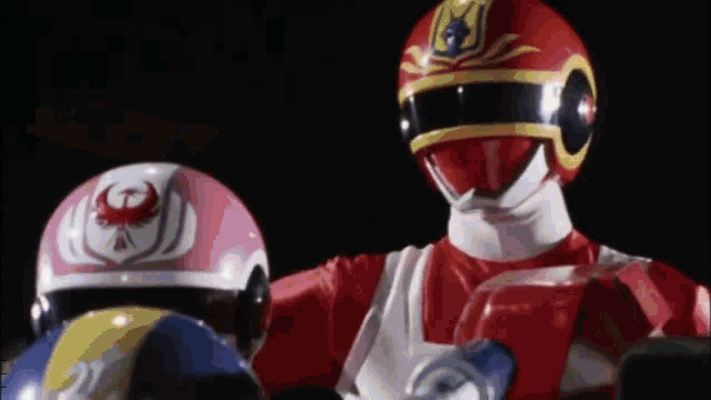 two power rangers are standing next to each other in a dark room .