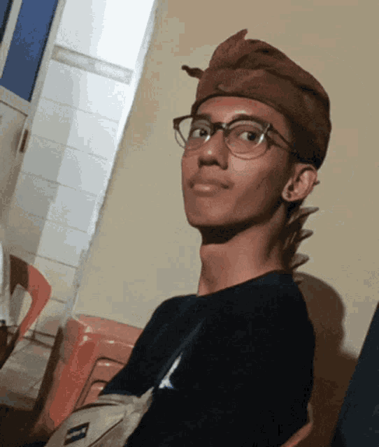 a young man wearing glasses and a brown turban