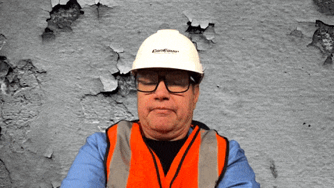 a man wearing an orange vest and a white hard hat that says ' carlton ' on it