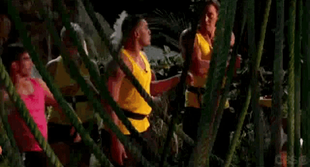 a group of people are standing in a jungle and one of them is saying `` watch out , loser '' .
