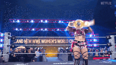 a woman in a wrestling ring with a sign that says and new wwe women 's world champion