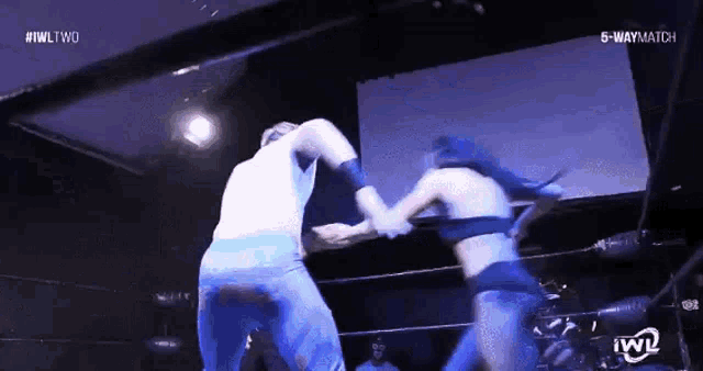 a man and a woman are wrestling in a ring with the words 5 way match on the screen behind them .