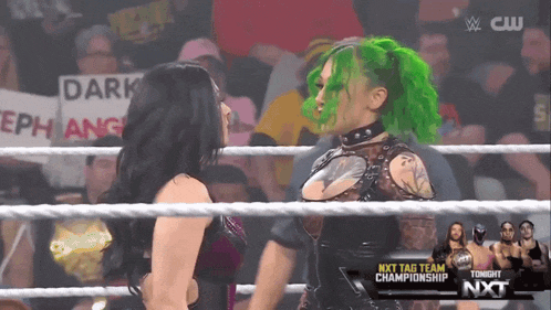 two women in a wrestling ring one with green hair