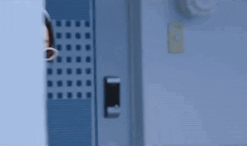 a person is peeking out from behind a blue door .
