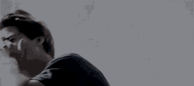 a man in a suit and tie is laying on a bed with his head down .