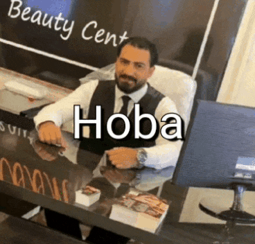 a man is sitting at a desk in front of a sign that says beauty center