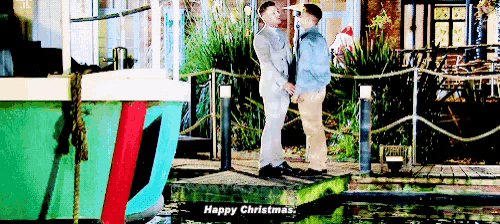 two men are standing next to each other on a dock and one of them is saying " happy christmas "