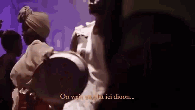 a group of people are dancing in a dark room with the words on wait onplat ici dioon written in yellow