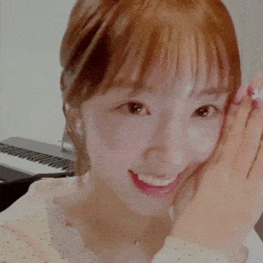 a woman covering her face with her hand in front of a piano keyboard