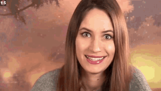 a woman with long hair is smiling for the camera .