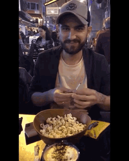a man sitting at a table with a bowl of popcorn in front of a sign that says public area