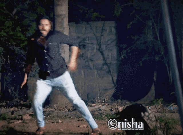 a man is dancing in front of a brick wall with the name onisha above him