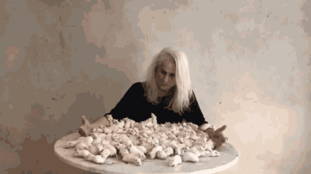 a woman is sitting on a table with a pile of mice on it