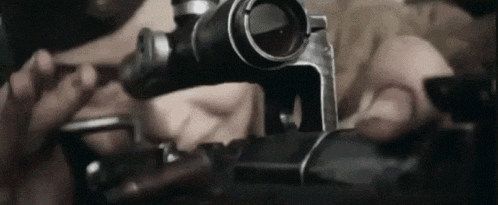 a close up of a person holding a gun with a scope .