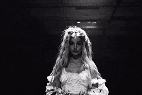 a black and white photo of a woman with long blonde hair in a white dress .